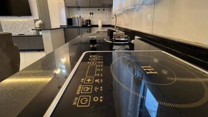A modern kitchen with a central island, built-in appliances, and a flat-screen TV. - LivLuxe Apartments 7 (Kampala)