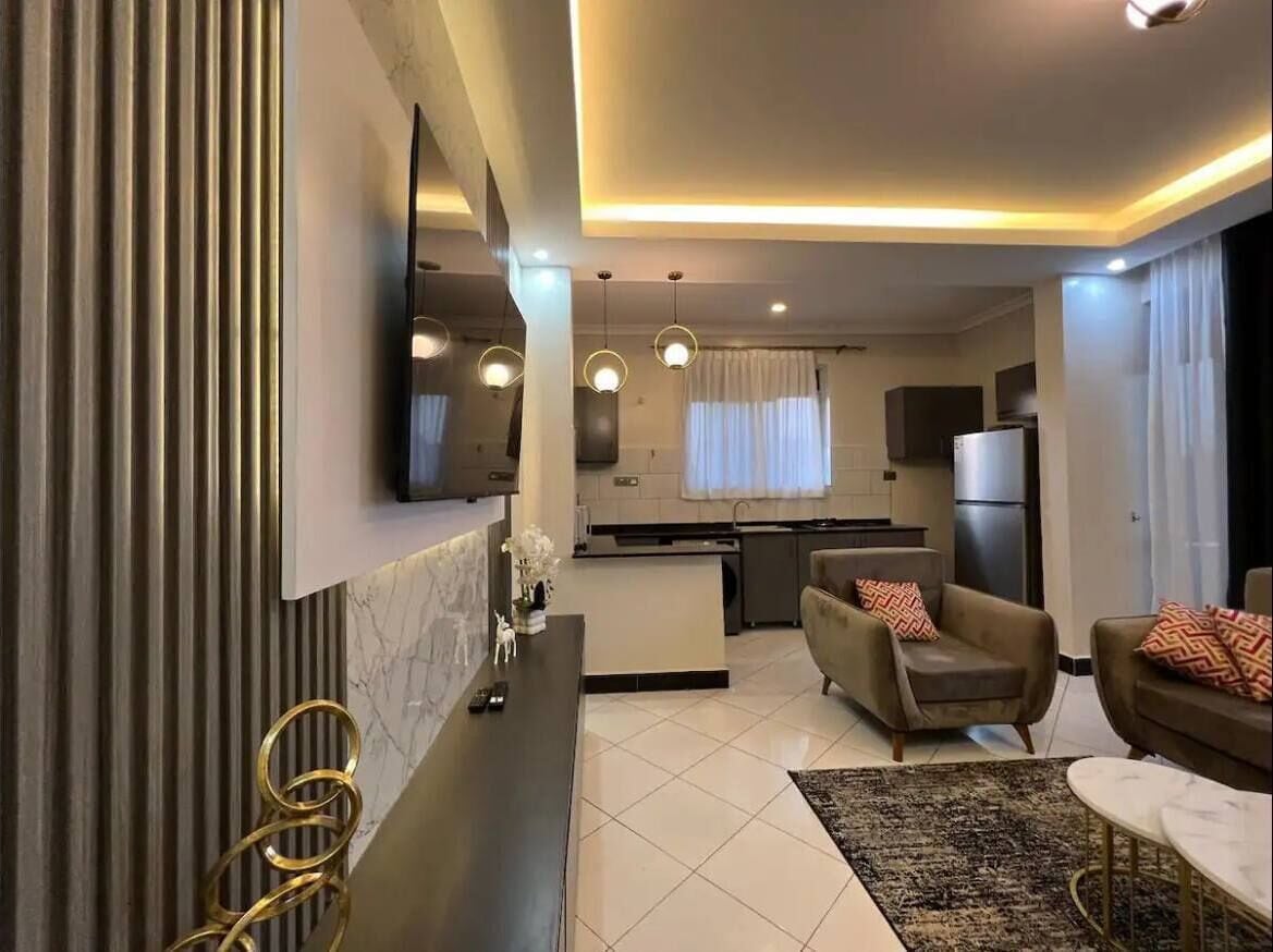 A modern living room with a sofa, a coffee table, and a TV mounted on the wall.