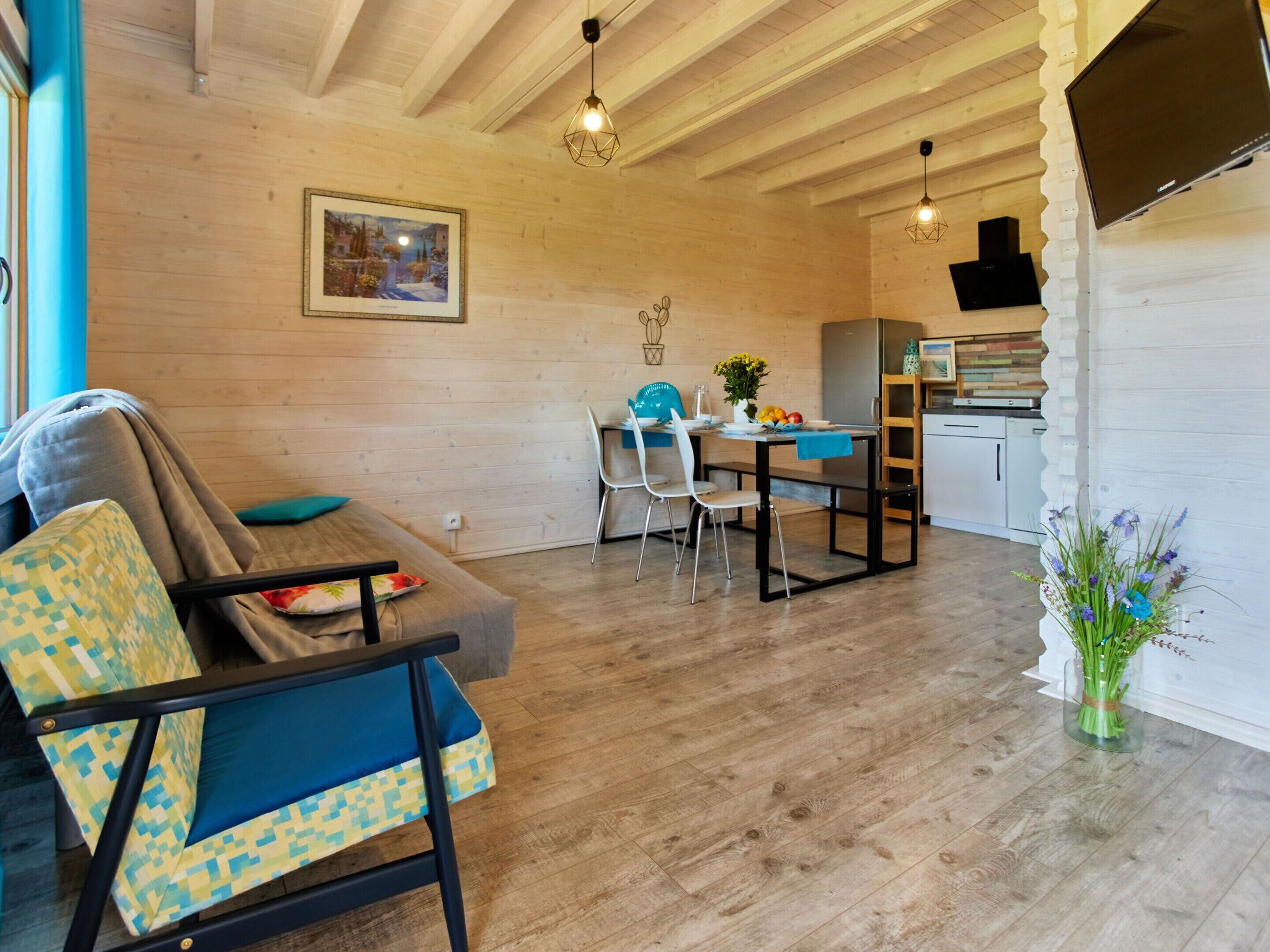 A cozy living room with a sofa and chairs, a dining area with a table and chairs, and a kitchen with a refrigerator and cabinets.