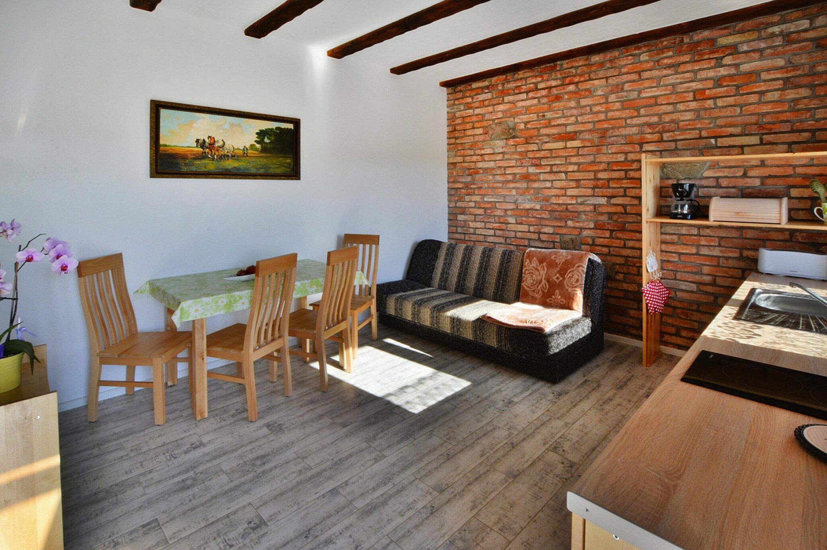 A cozy living room with a brick wall, wooden furniture, and a painting on the wall.
