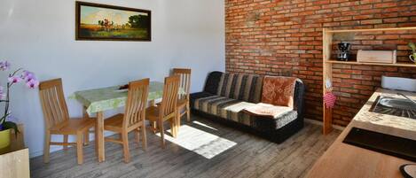 A cozy living room with a brick wall, wooden furniture, and a painting on the wall.