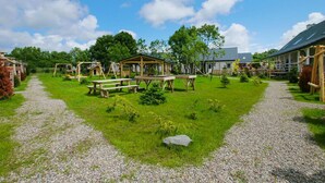 A rustic outdoor area with picnic tables, a wooden swing set, and a covered seating area. - Apartment in a Family Holiday Resort (Postomino)