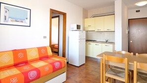 Un espacio habitable funcional con sofá, mesa de comedor y kitchenette.