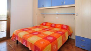 Un dormitorio con cama, un armario azul y una ventana.