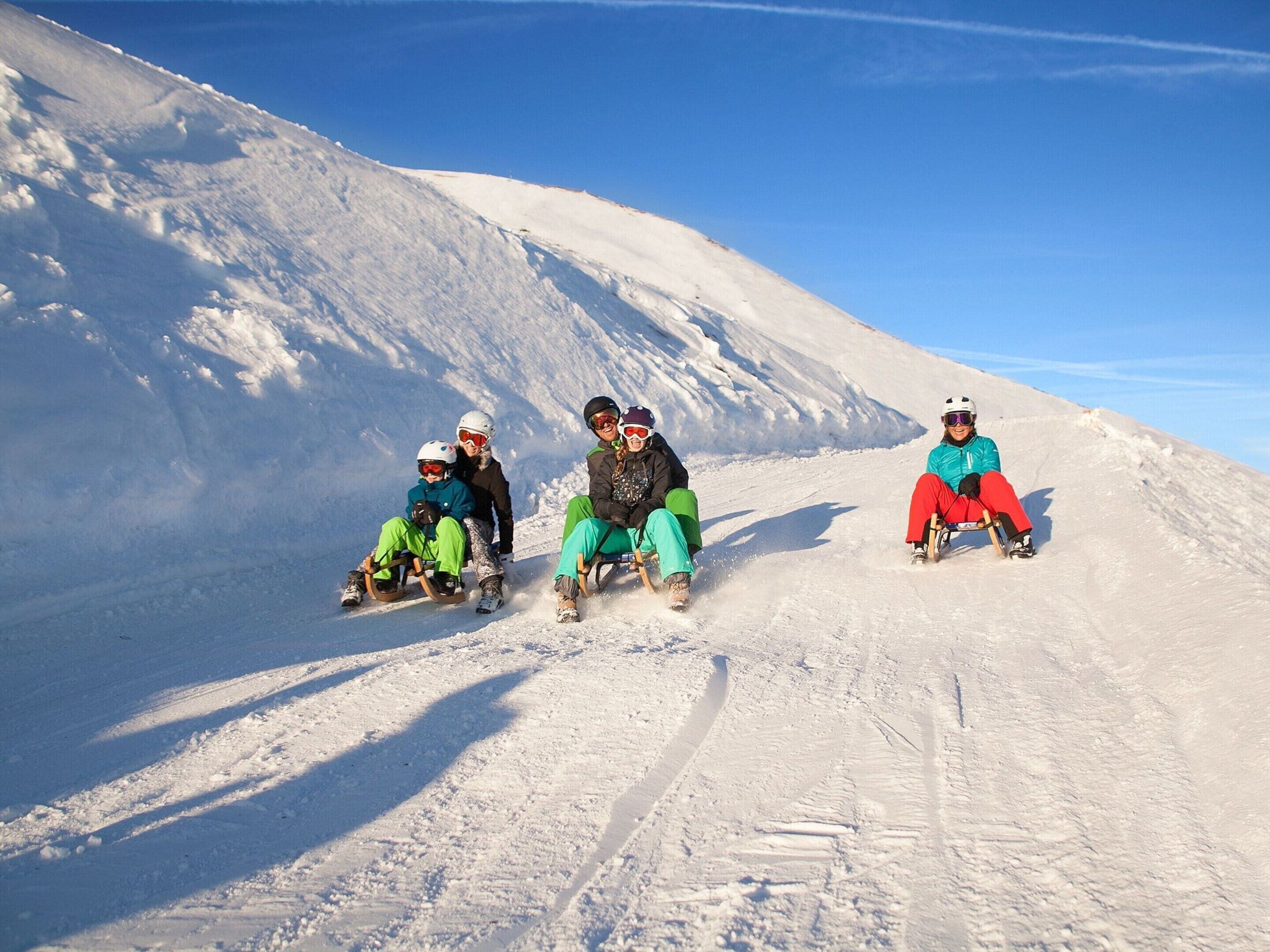Een groep mensen glijdt op een besneeuwde helling.