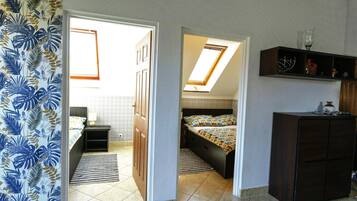 Un dormitorio con cama, mesita de noche, cómoda y tragaluz.