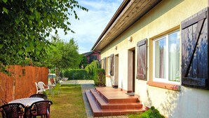 En bostadsbyggnad med en stenlagd uteplats, utomhusmöbler och ett trästaket.