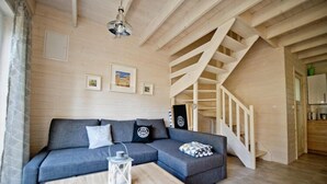 Un soggiorno moderno con un divano angolare grigio, un tavolino in legno e una scala in legno.