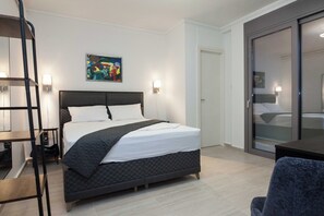 Una habitación de hotel moderna con una cama grande, un escritorio y un armario.