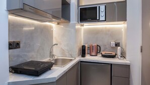 Una cocina moderna con placa de inducción integrada, pileta de acero inoxidable y microondas.