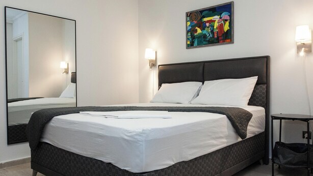 Una habitación de hotel moderna con una cama grande, una mesita de noche y un cuadro en la pared.