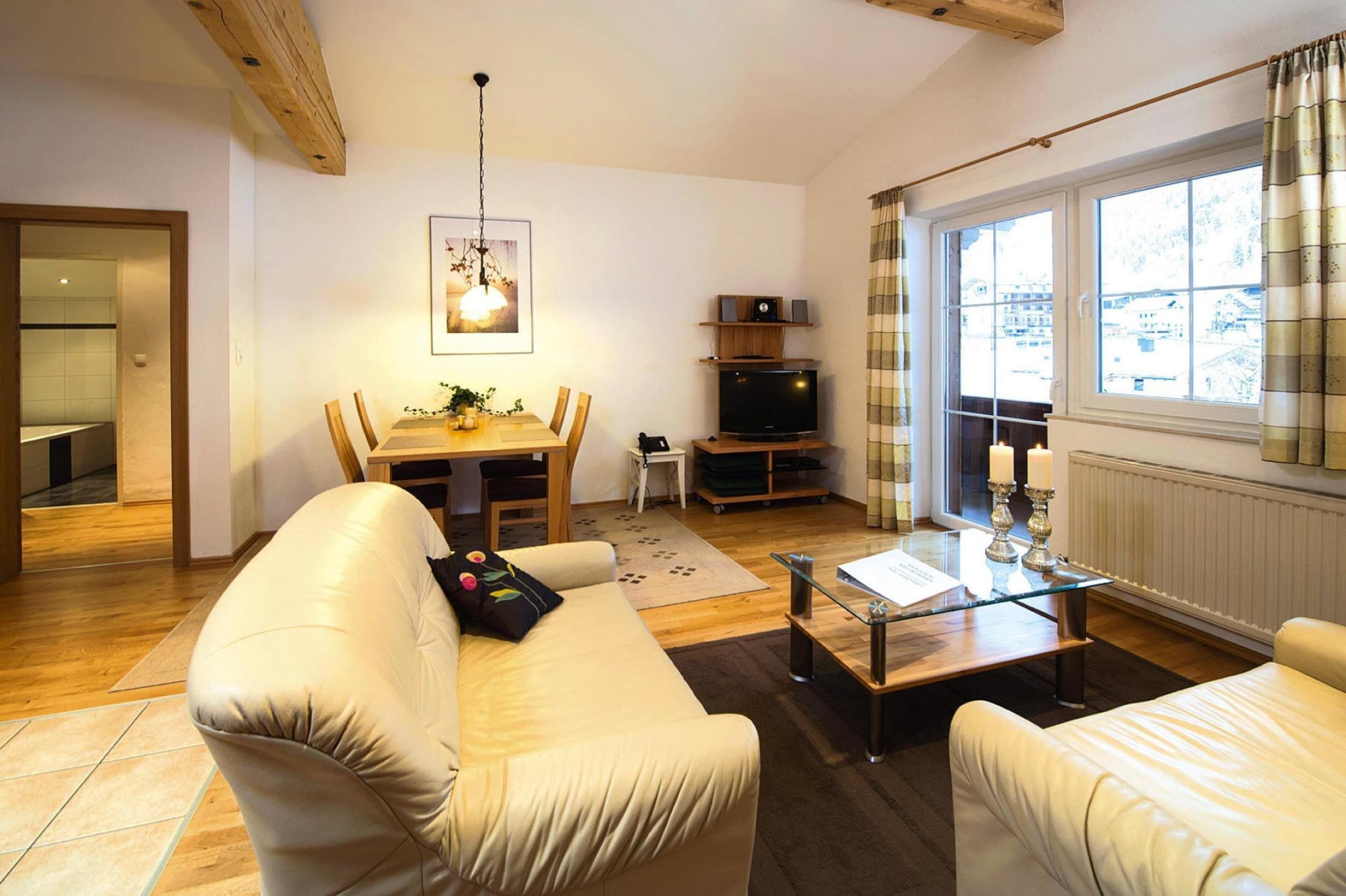 A modern living room with a sofa, a coffee table, a TV, and a dining area with a table and chairs.