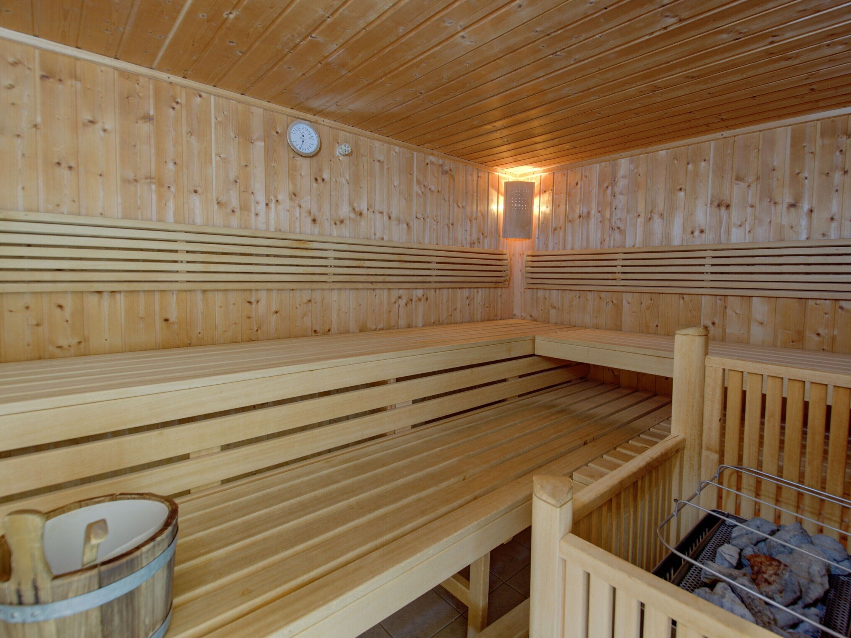 Een sauna met houten banken en een metalen rek voor stenen.