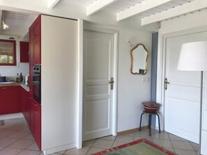 A kitchen with red cabinets, a white door, and a mirror on the wall. - Très Joli Chalet Confortable, Cosy. Drôme- Vercors. Idéal Famille/télé Travail (Saint-Julien-en-Vercors)