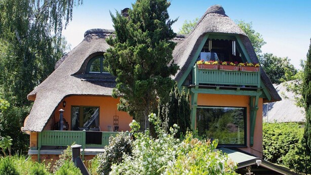Ett hus med ett halmtak och en grön veranda.