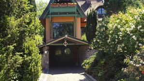 Ett traditionellt hus med ett halmtak, en grön veranda och en skorsten av sten.