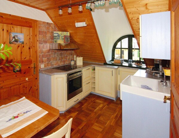 A kitchen with wooden cabinets, a stove, a sink, and a window. - Ferienhaus, Damerow (Jabel)