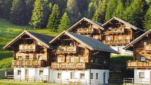A cluster of wooden cabins with balconies, set in a lush green landscape. - Apartment in Lienz With a Balcony (Thurn)