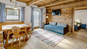 A rustic wooden interior with a dining table, chairs, a sofa, and a TV. - Apartment in Lienz With a Balcony (Thurn)