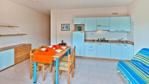 Una cocina compacta con armarios azul claro, una mesa de comedor con sillas y un sofá.