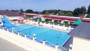 Ein Swimmingpool mit blauer Rutsche, Liegestühlen und Sonnenschirmen.