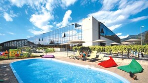 A swimming pool with lounge chairs and bean bags, a modern building with glass windows, and a clear blue sky. - Residence Riviera Palace, Loano (Loano)