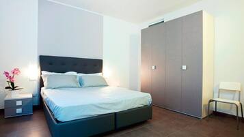 Ein modernes Schlafzimmer mit Bett, Nachttischen, einem Kleiderschrank und einem Sessel.