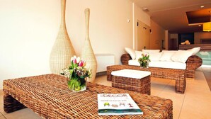 A modern living room with wicker furniture, a magazine on the coffee table, and a view of a pool area. - Residence Riviera Palace, Loano (Loano)