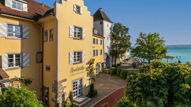 Ein gelbes Gebäude mit einem Schild, auf dem "Schnitzelhaus" steht, und einem Kopfsteinpflasterweg, der zum Wasser führt.