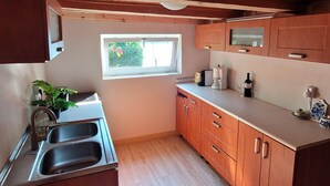 A compact kitchen with wooden cabinets, a window, and a sink. - Holiday Home Right on the Lake, Florczaki (Lukta)
