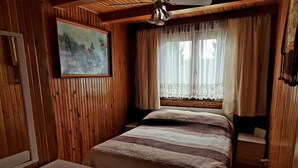 A wooden-paneled room with a bed, a painting, and a window with curtains. - Holiday Home Right on the Lake, Florczaki (Lukta)