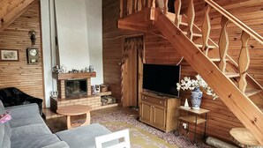 A cozy cabin interior with a fireplace, wooden staircase, and a television. - Holiday Home Right on the Lake, Florczaki (Lukta)