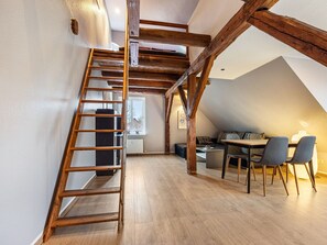 A loft-style room with a wooden staircase, a dining area with a table and chairs, and a cozy seating area with cushions. - Studio in Buchholz am Muritzsee (Buchholz)