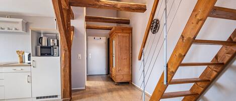 A kitchen with wooden beams, a microwave, and a cabinet.