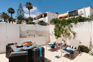 An outdoor dining area with a table set for breakfast, a white fence, and a view of the neighborhood. - Holiday Flat With sea View in Maspalomas (San Bartolomé de Tirajana)