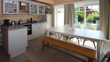 Una cocina moderna con armarios blancos, encimera de madera y un comedor con mesa y banco blancos.