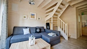 Un salon moderne avec un canapé d’angle gris, une table basse en bois et un escalier en bois.
