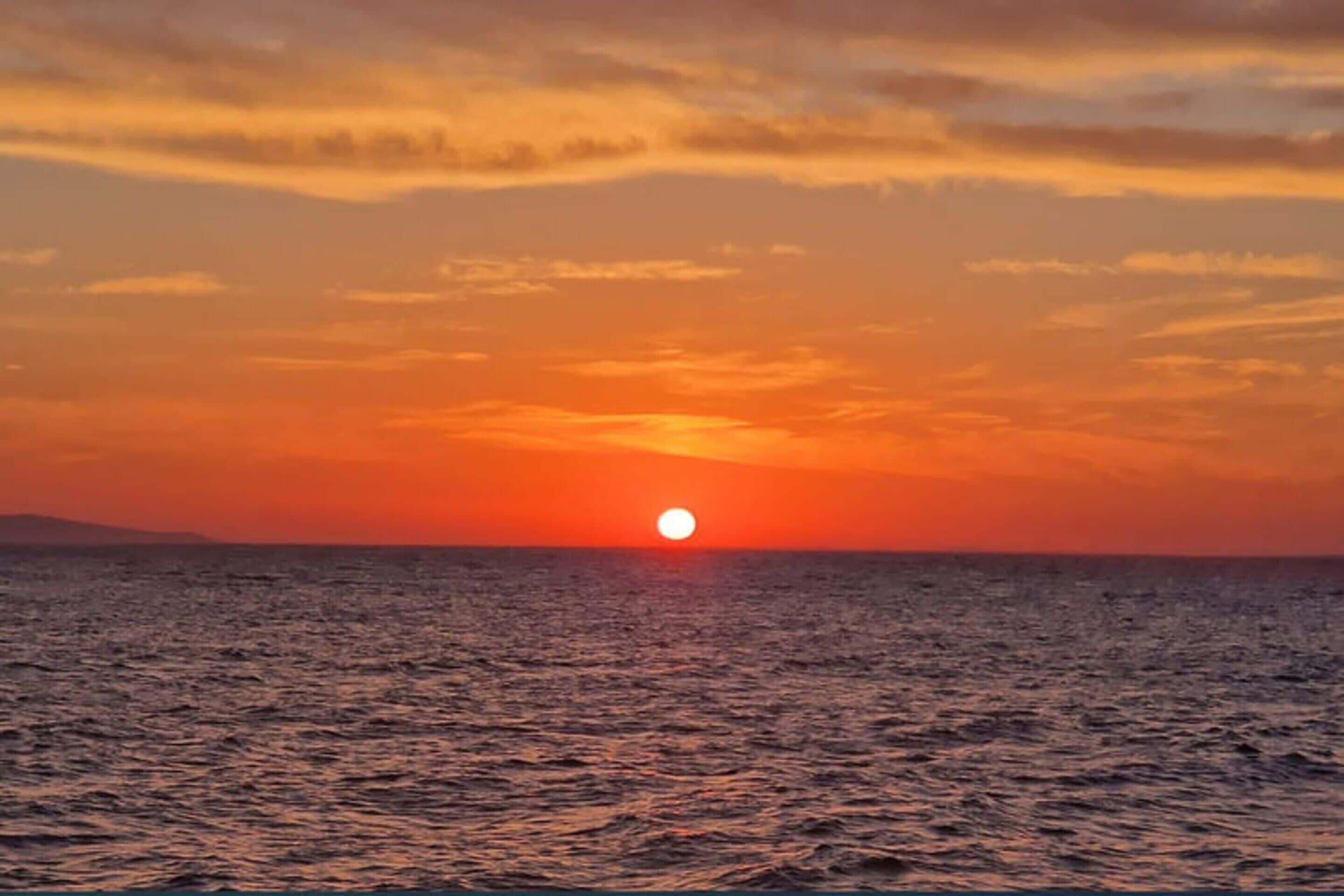 Un coucher de soleil sur l’océan, avec un horizon dégagé.