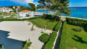 Une propriété située en bord de mer, dotée d’une allée pavée, d’une pelouse verdoyante et offrant une vue sur la mer.