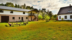 A courtyard with two buildings, a wooden bench, and bicycles. - Holiday Apartment in the Countryside, Biskupice (Biały Bór)