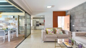 A modern living room with a sofa, a glass coffee table, and a dining area with a table and chairs. - Holiday Home, Maspalomas (San Bartolomé de Tirajana)