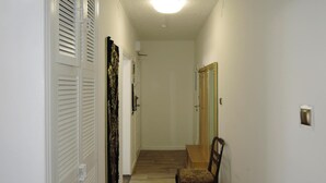 Un pasillo con suelo de madera, una silla y una puerta.