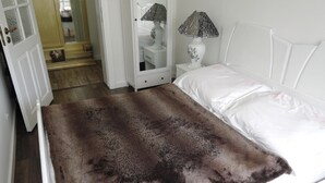 Un dormitorio con cama, mesita de noche, lámpara y espejo.