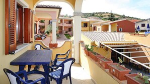 Une terrasse avec une table et des chaises, des plantes en pot et une vue sur les bâtiments voisins.