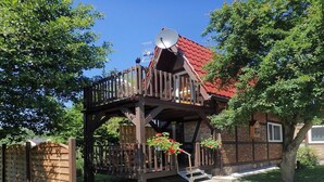 Punaisella katolla varustettu puutalo, jossa on satelliittiantenni ja parveke.
