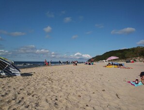 A sandy beach with people, umbrellas, and tents. - Bungalow in Kolczewo With Parking Space (gmina Wolin)