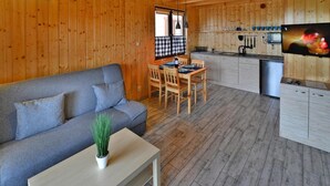 A cozy cabin interior with a sofa, dining table, and kitchen area. - Holiday Home in Sianozety Near the Beach (Ustronie Morskie)