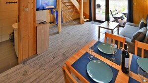 A wooden interior with a dining area, a TV, and a staircase. - Holiday Home in Sianozety Near the Beach (Ustronie Morskie)