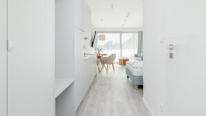 Une chambre d’hôtel moderne et minimaliste, dotée d’une kitchenette, d’un coin repas et d’une chambre avec une grande fenêtre.