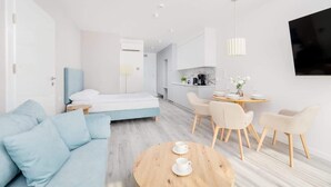 Une chambre d’hôtel moderne équipée d’un lit, d’un canapé, d’une table à manger avec des chaises et d’un téléviseur fixé au mur.